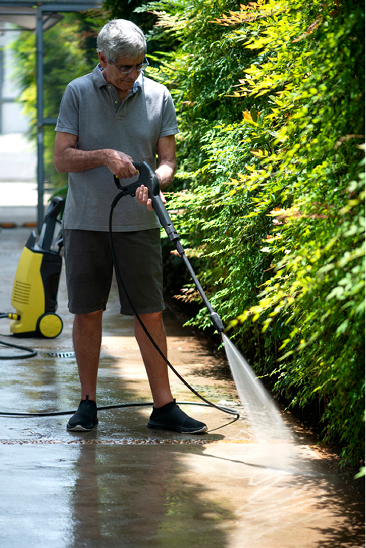 Man pressure washing outdoor pavement